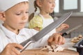 Little boy wielding a big knife chopping mushrooms