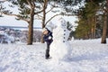 Little boy in winter fun with snowman. Active outdoors leisure with children in winter. Kid with warm hat, hand gloves Royalty Free Stock Photo