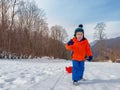 Little boy in winter outfit pull red sledge mounting the slope Royalty Free Stock Photo