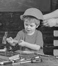 Little boy working with hammer. Daddy taking care of sons safety. Male hands holding orange protective helmet. Small kid Royalty Free Stock Photo