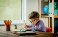 Little boy write on blank paper on desk near the window. Back to school. Educate at home and doing homework Royalty Free Stock Photo