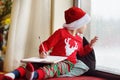 Little boy writing the letter to Santa and looking by window. Child dreams of a gift that he can receive Royalty Free Stock Photo