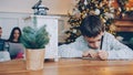 Little boy writing letter to Santa while parents using laptop before winter holidays