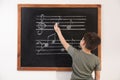 Little boy writing music notes on blackboard Royalty Free Stock Photo