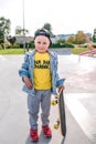 Little boy of 3-5 years old laughs, plays, relaxes, on summer autumn day in city park, fun casual clothes, skateboard Royalty Free Stock Photo