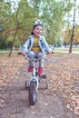 Little boy 3-5 years old, learning to ride bike, autumn day, casual warm clothes. Denim with baseball cap. Driving