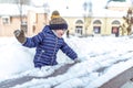 A little boy of 3-6 years old plays in the winter in the city, happy having fun playing snowballs, collecting snow from Royalty Free Stock Photo