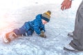 Little boy, 2-3 years old, winter uniform, blue overalls hat, fell on ice skates. The concept of first lesson skating Royalty Free Stock Photo