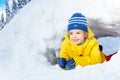 Little boy in yellow crawl through snow tunnel