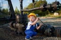 Little boy exploring working tools outdoors near pipeline.