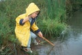 Little boy in yellow raincoat by stream Royalty Free Stock Photo