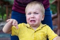 Little boy in a yellow T-shirt is badly upset and crying. Tears on her cheek