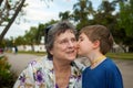 Little Boy With a Yellow Yarn Necklace Kisses His Grandmother on Royalty Free Stock Photo