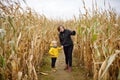 Little boy with young mother having fun on pumpkin fair at autumn. Person walking among the dried corn stalks in a corn maze Royalty Free Stock Photo