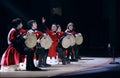 Little boys dressed in national costumes playing Georgian folk musical instrument doli on stage.