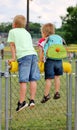 Little boys on a fence looking onto a baseball field