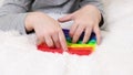 Little boys hands are playing an educational game. Colorful antistress sensory toy fidget push pop it in toddler's