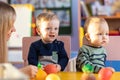 Little boys playing indoors at home or kindergarten. Adorable children with educator play plastic vegetables and fruits.