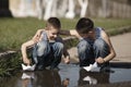Little boys playing with paper boats in puddle Royalty Free Stock Photo