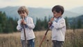 Little boys playing on woodwind wooden flutes - ukrainian sopilka on meadow of Carpathian mountain. Duet folk music