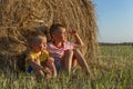 Little boys are sitting in a field with hay with a setting sun. Farming and nature Royalty Free Stock Photo