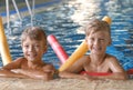 Little boys with swimming noodles in pool