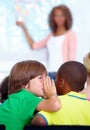 Little boys, whisper and classroom in ear at classroom for secret, gossip or communication at school. Male person Royalty Free Stock Photo