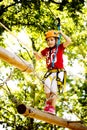 Little brave caucasian girl at outdoor treetop climbing adventure park