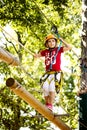 Little brave caucasian girl at outdoor treetop climbing adventure park