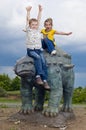 Little brave children on a dinosaur in a park