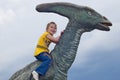 Little brave girl on a dinosaur in a park