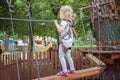 Little brave girl overcomes the obstacle in the rope park. Royalty Free Stock Photo