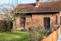 Little brick house with a small garden, tree and fence