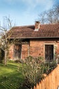 Little brick house with a small garden, tree and fence