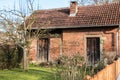 Little brick house with a small garden, tree and fence