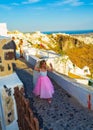 Little bridesmaid walking on narrow panoramic street in Imerovigli Santorini Greece