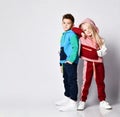 Dark haired boy and blonde girl in stylish jym suits standing back to back. Portrait isolated on light grey, copy space Royalty Free Stock Photo