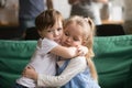 Little brother hugging upset sister sitting on couch