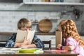 little brother and sister covering faces with books and looking