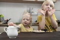 Little brother and sister are having breakfast in kitchen. Albino children