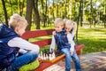 Little brothers playing chess with sister on bench in park. Children intelligence development. Family leisure time. Kids playing Royalty Free Stock Photo