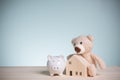 Little brown teddy bears with piggy banks, and wood house models on an old wooden table with copy space. Savings money to buy a Royalty Free Stock Photo