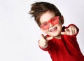 Little brunet male in sunglasses, red jumper. He smiling, pointing at you by forefingers, posing isolated on white Royalty Free Stock Photo