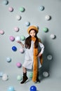 Little brunette asian girl in oversized shirt dress, brown beret and scarf, boots. She posing with balloons on blue background. Royalty Free Stock Photo