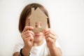 Little girl holding paper house in front of her face. Protect your home concept Royalty Free Stock Photo