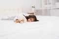 Little brunette girl lying with teddy bear on bed at home