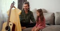 A little brunette girl in a pink dress sits on the sofa near her father who steams a pink dress using a special