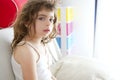 Little brunette girl sit on sofa window light