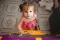 A little brunette girl with two ponytails at home in the game room near the blackboard with chalk in her hands. Top view Royalty Free Stock Photo