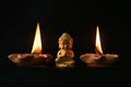 a little Buddha statue and burning candles on a black background Royalty Free Stock Photo